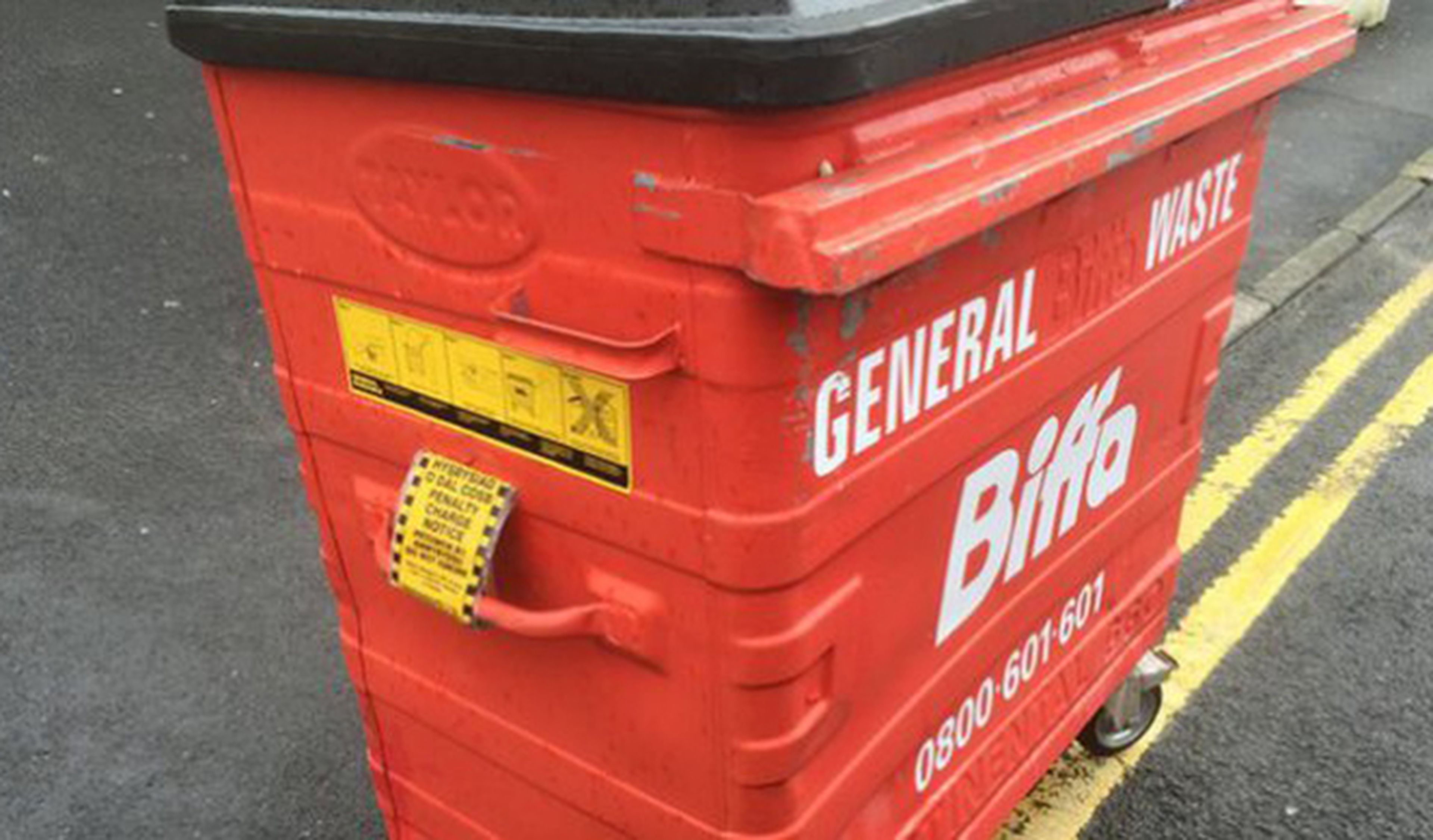 Un policía multa un contenedor de basura mal estacionado