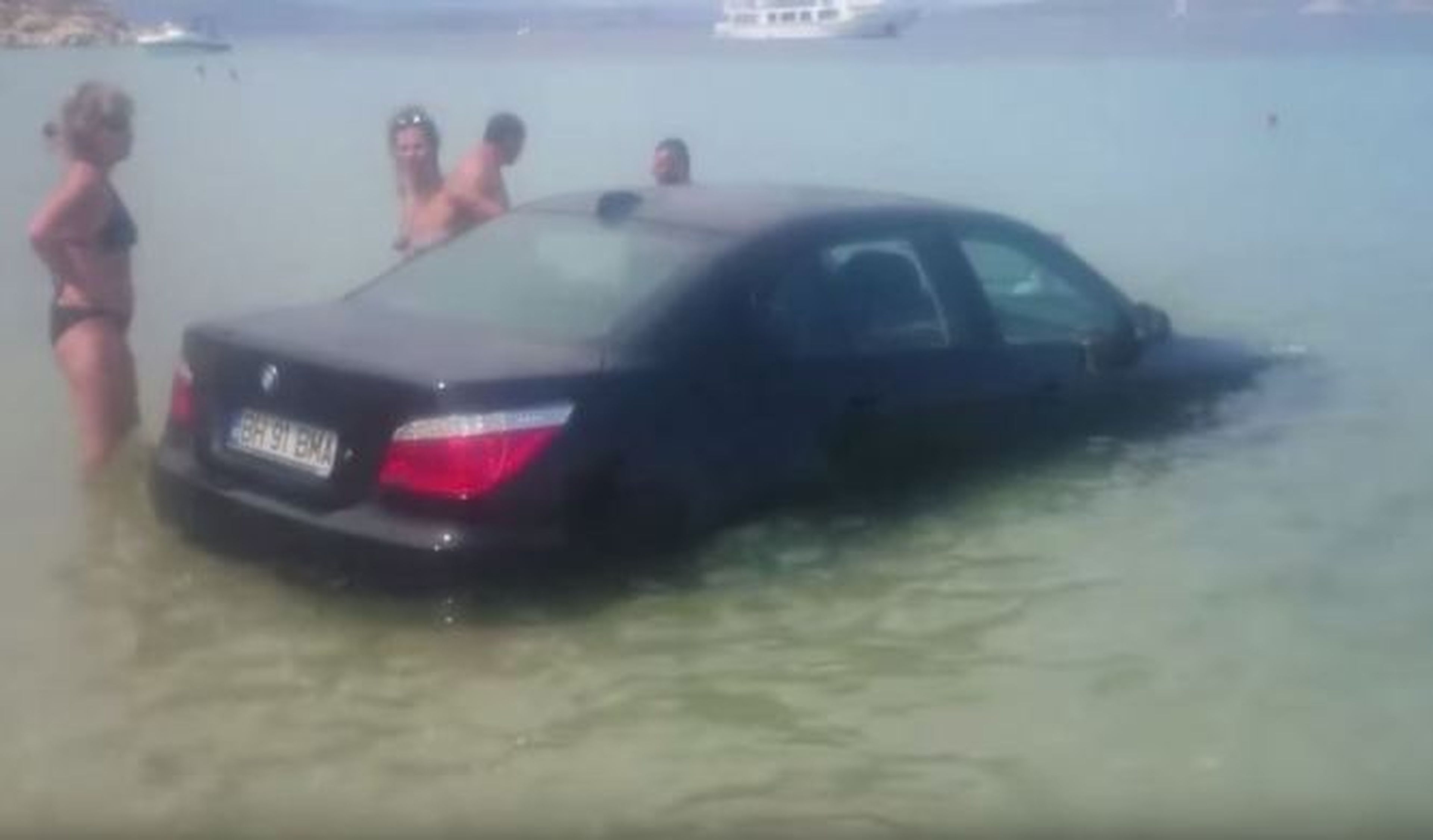Aparca su BMW Serie 5 en una playa con bañistas