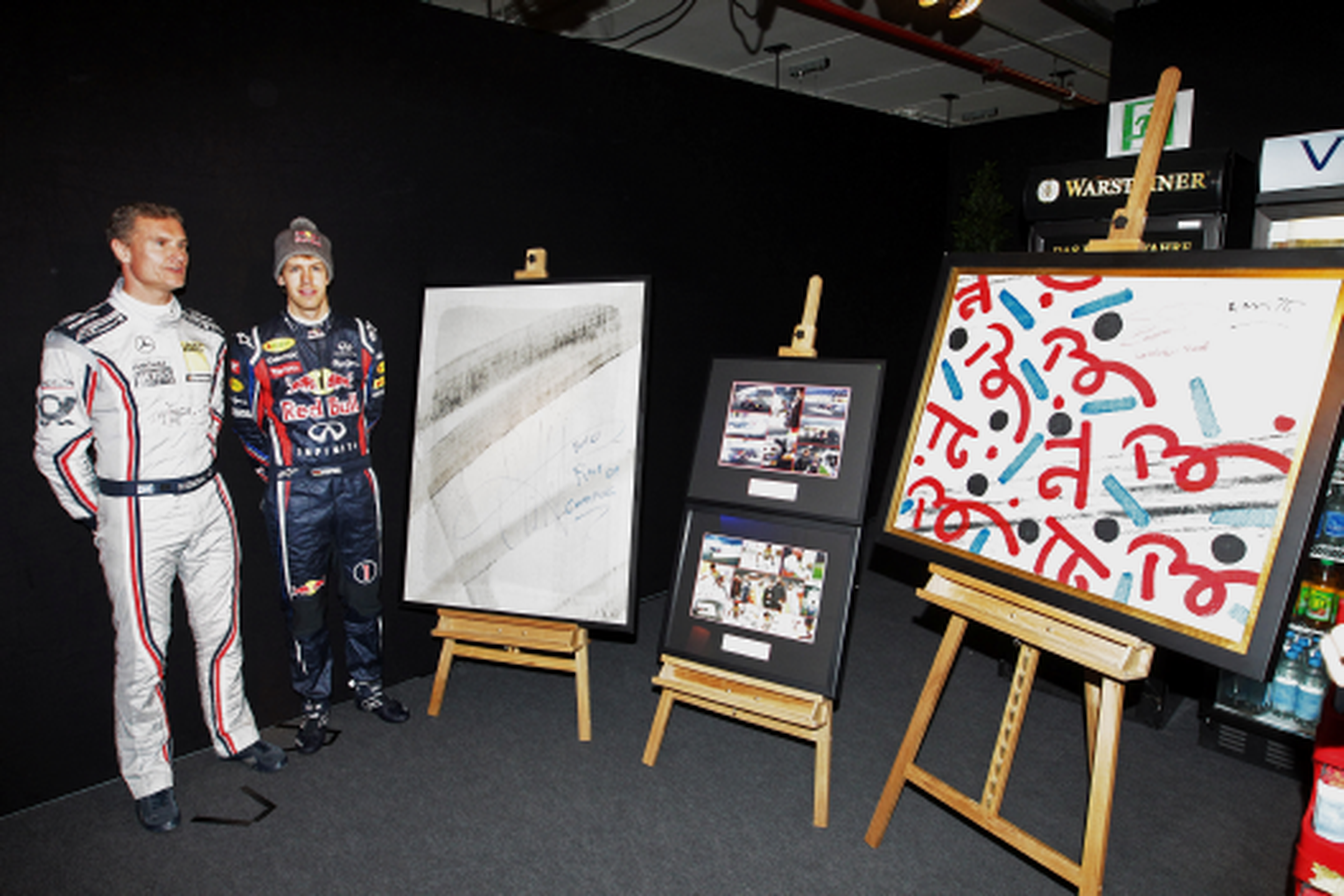 Sebastian Vettel presentando las obras de arte realizadas con sus trompos