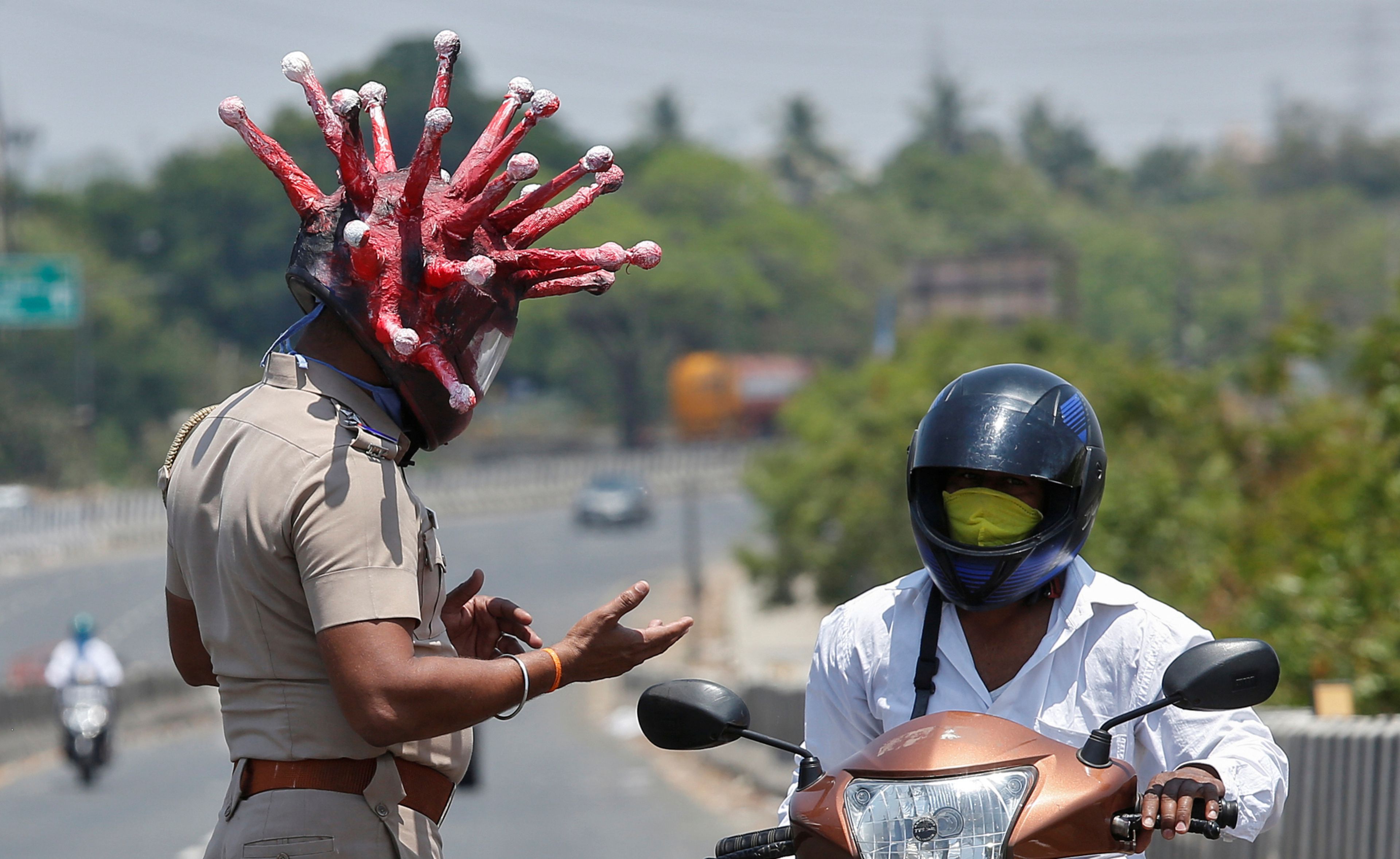 Un policía de Chennai (India) pide la documentación a un motorista mientras luce un casco que imita al coronavirus