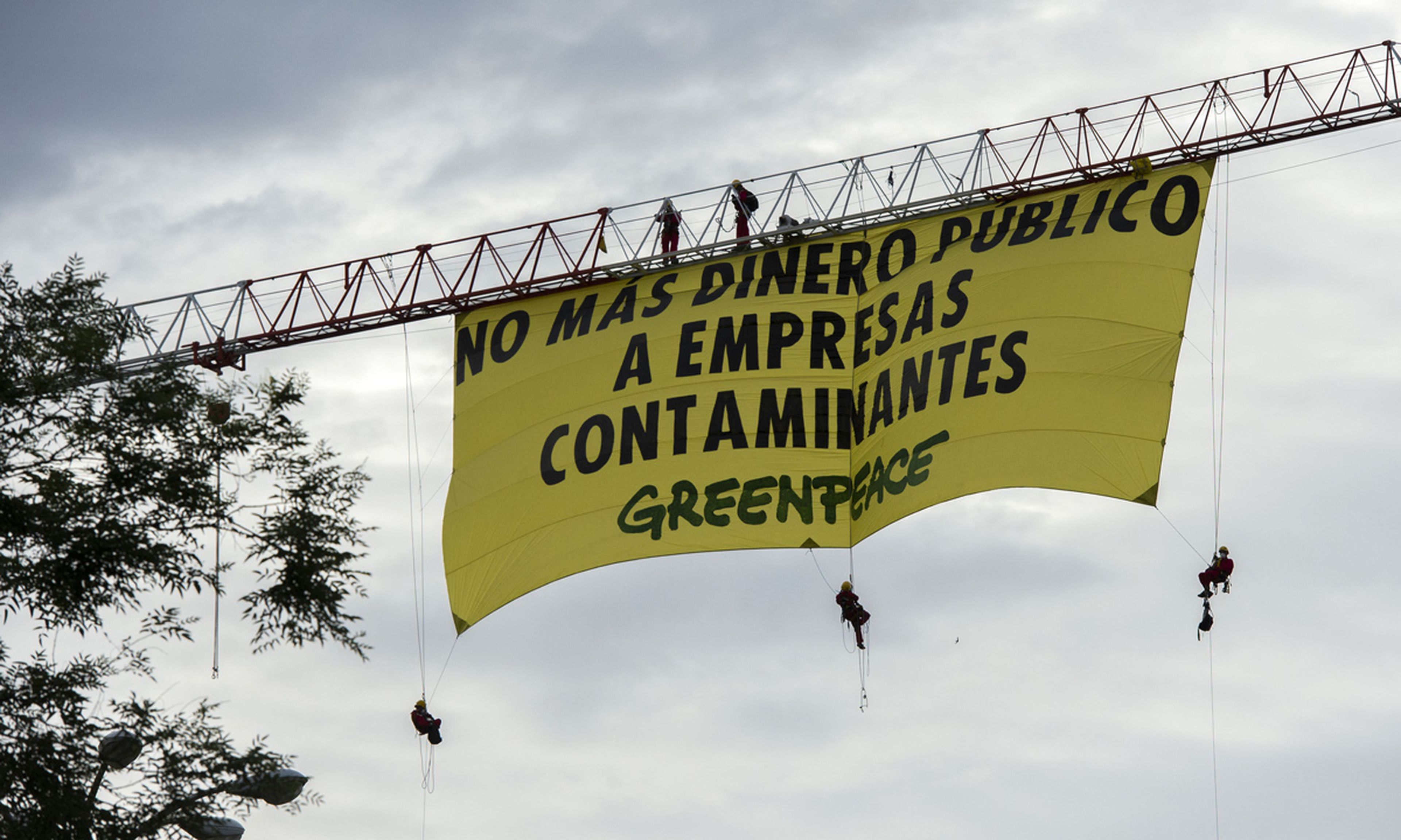 Los ecologistas han empleado una grúa para colgar su cartel en la Castellana