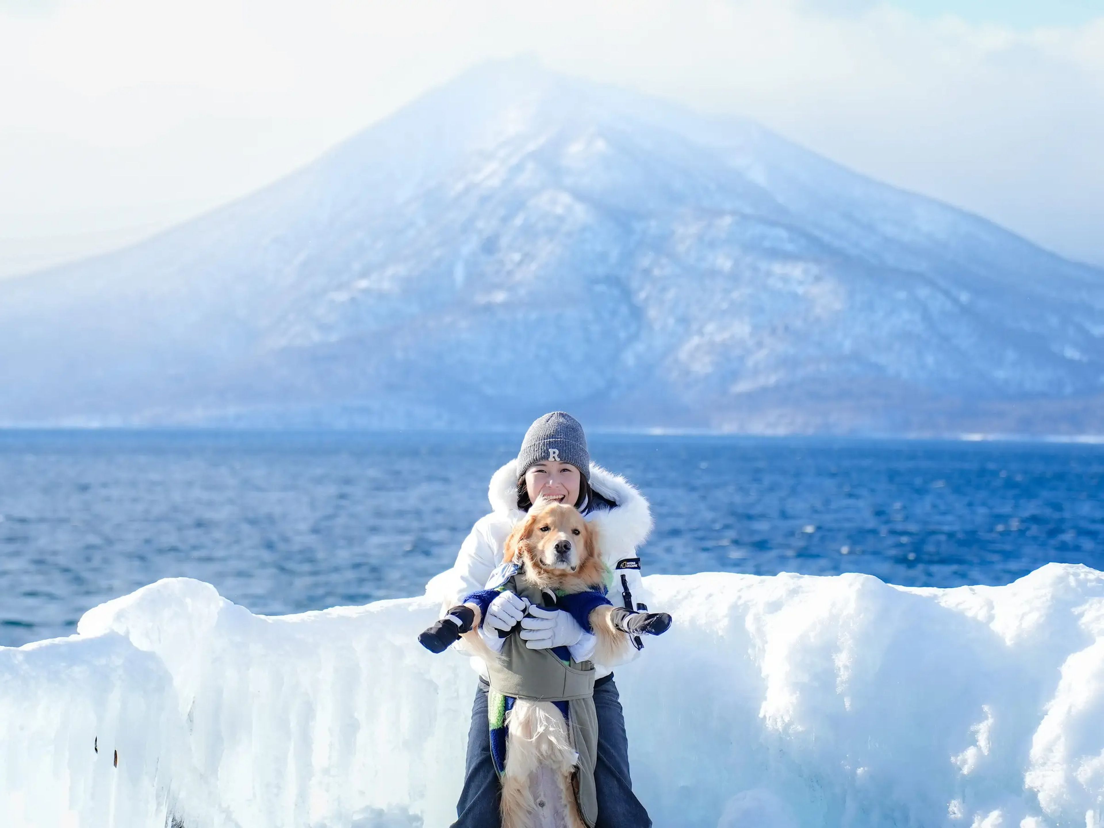 Woman posing with golden retriever in Japan with mountain int he background