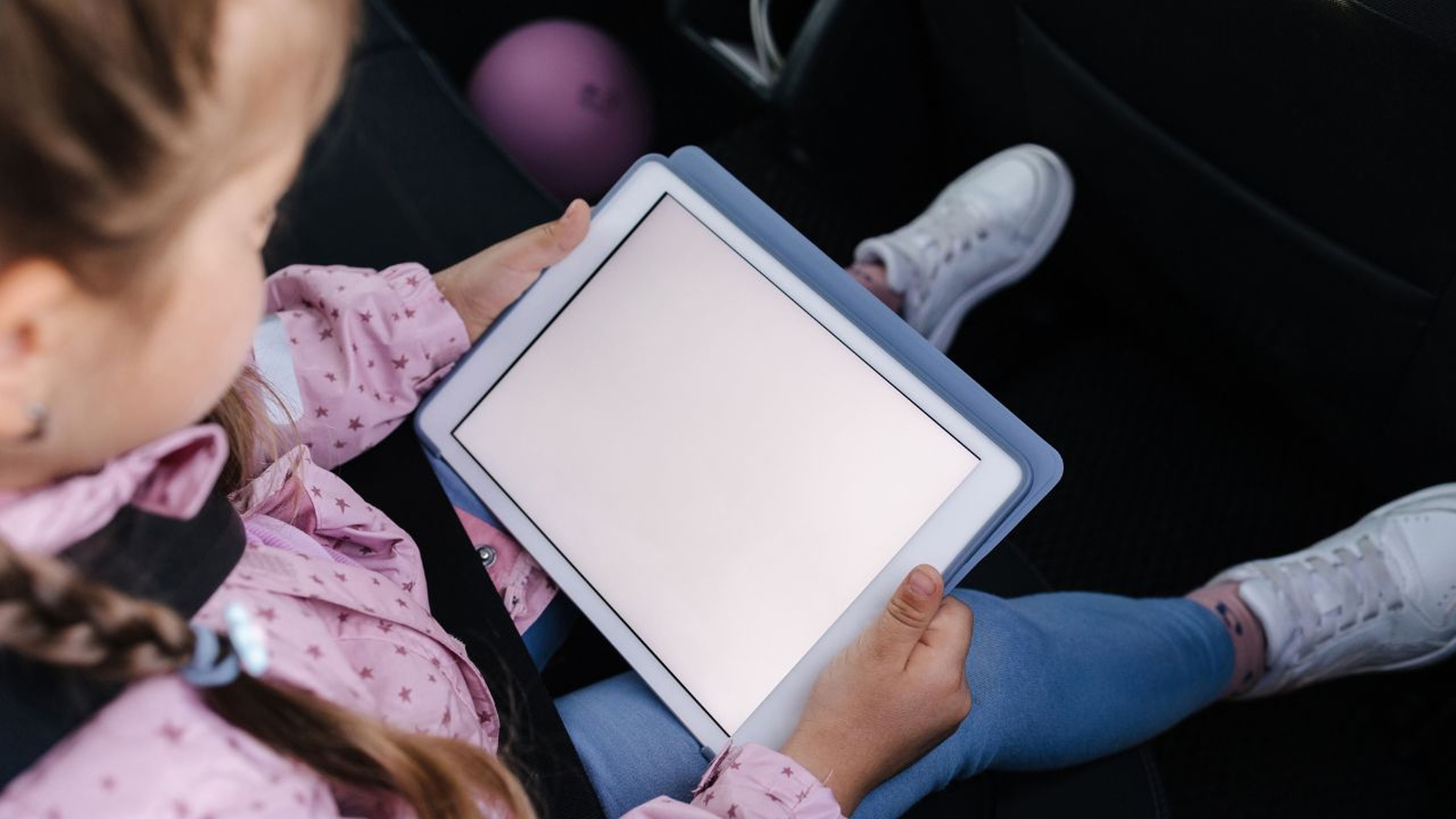 Niña jugando con la tablet en el coche