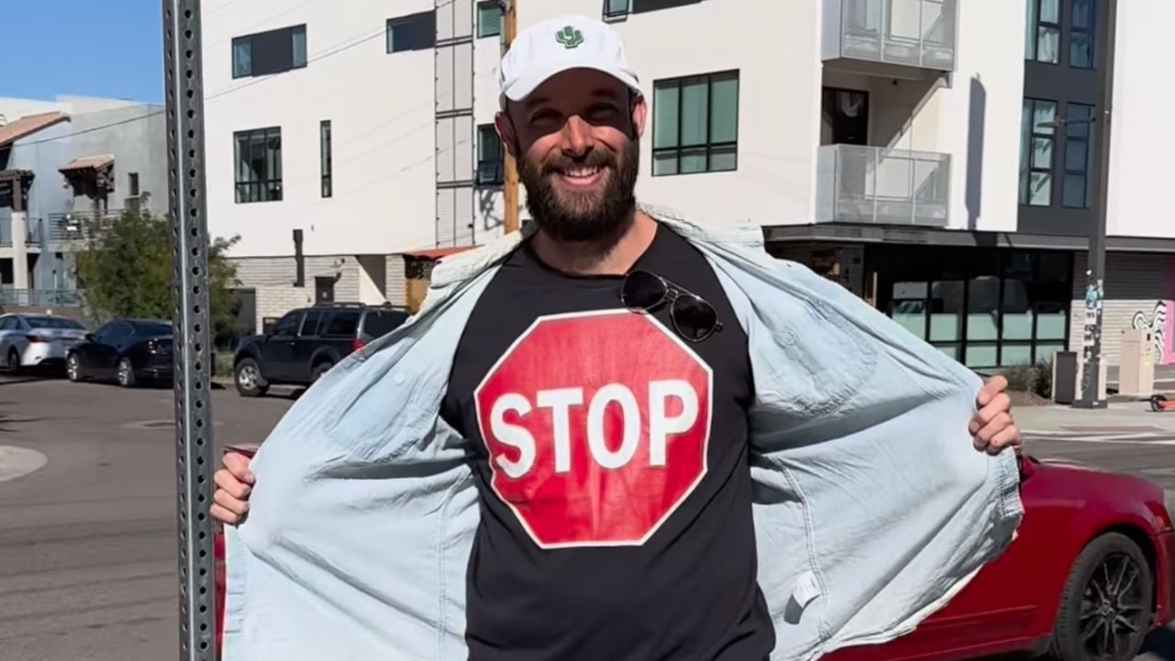 Un hombre detiene un Jaguar I-Pace de Waymo con una camiseta de una señal de stop